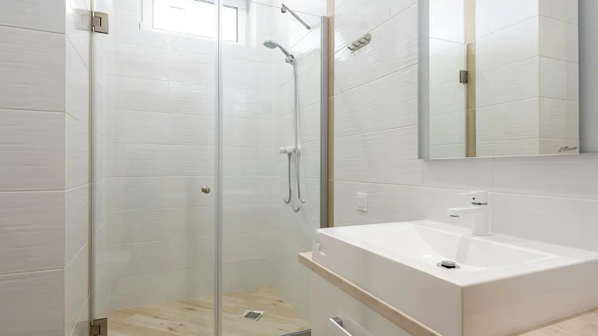 Bright clean modern bathroom with white tiles and glass shower cabin — the long-term result of effective DIY mold removal and consistent moisture prevention