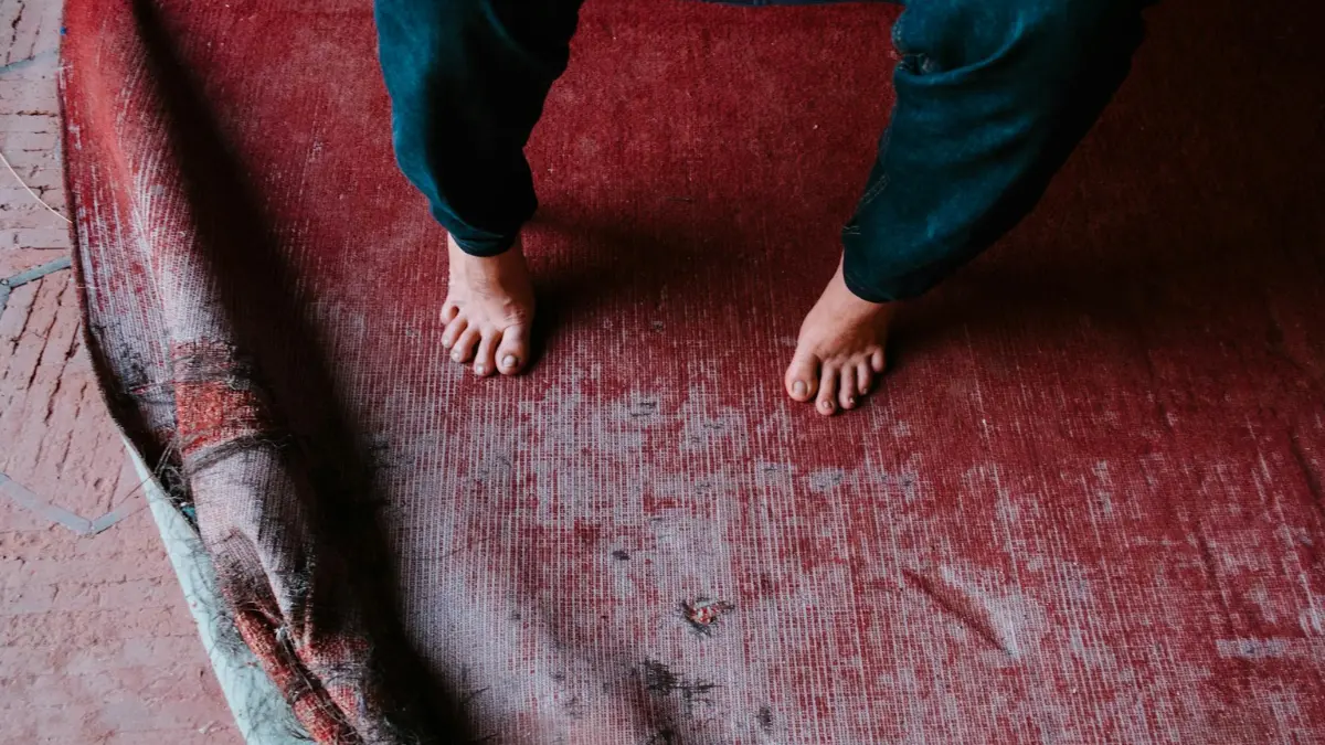 Person in white socks standing on a clean red geometric bedroom rug in a dry room preventing mold in carpet.