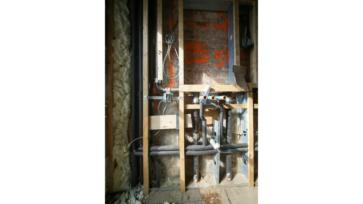 Mold Removal inspection area showing exposed wood studs, plumbing lines, and wiring inside an opened wall.