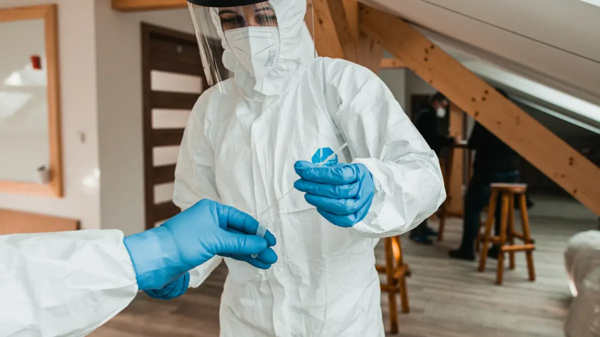 Mold Removal safety gear including protective coveralls, respirator, face shield, and blue gloves during cleanup preparation.