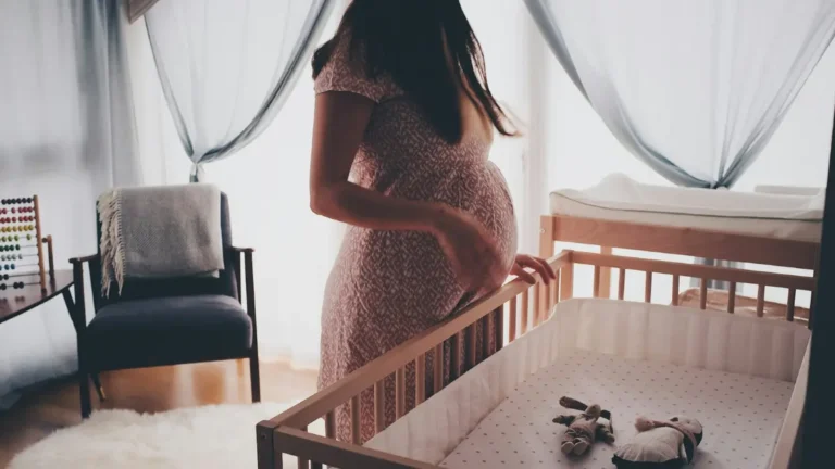 Pregnant woman stretching by a window at home, concerned about indoor air quality and mold exposure during pregnancy.