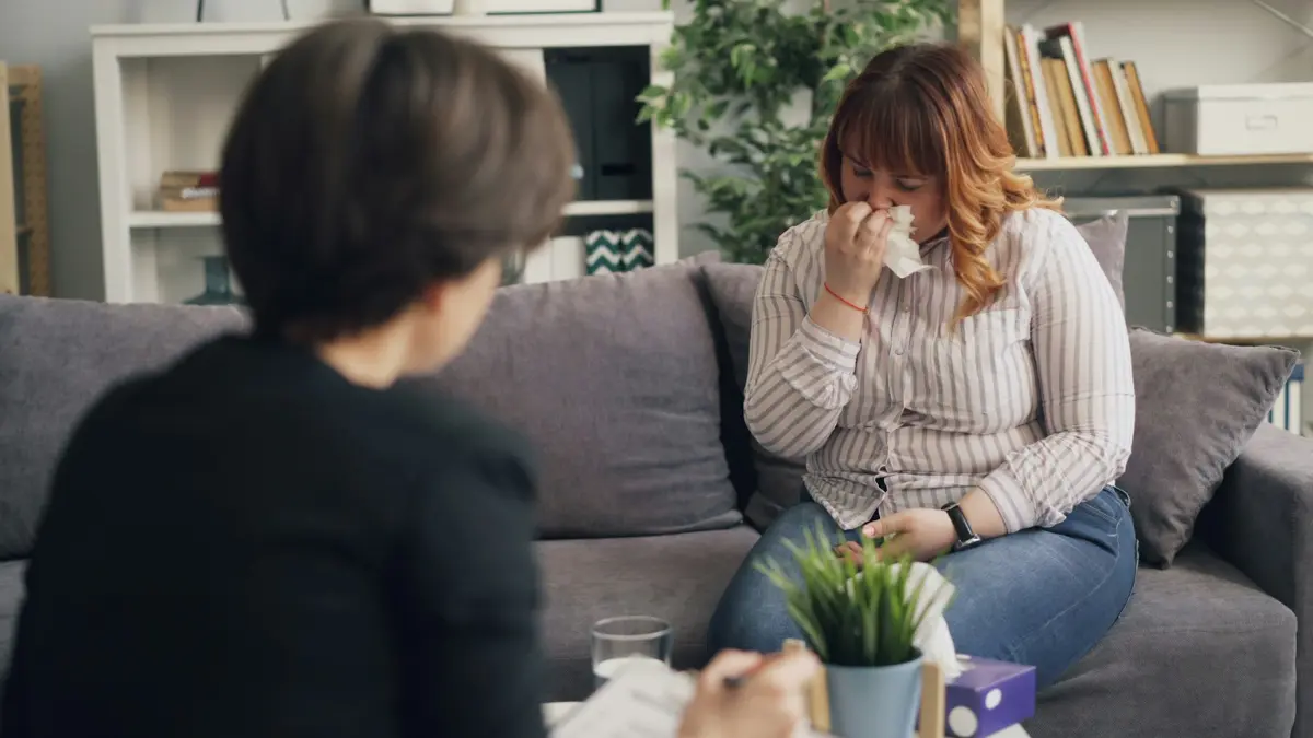 Woman covering her mouth with a tissue while experiencing respiratory symptoms from mold exposure during pregnancy.
