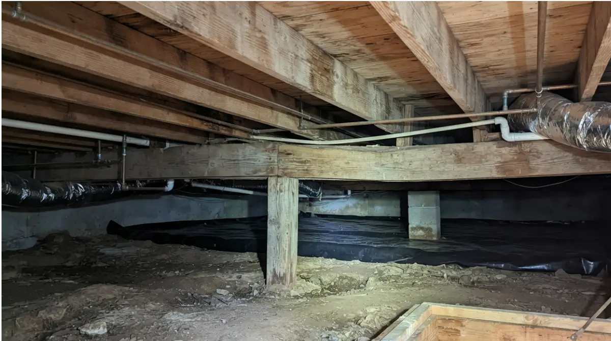 Sagging Floors with visibly bowed wooden joists and a support beam in a residential crawl space